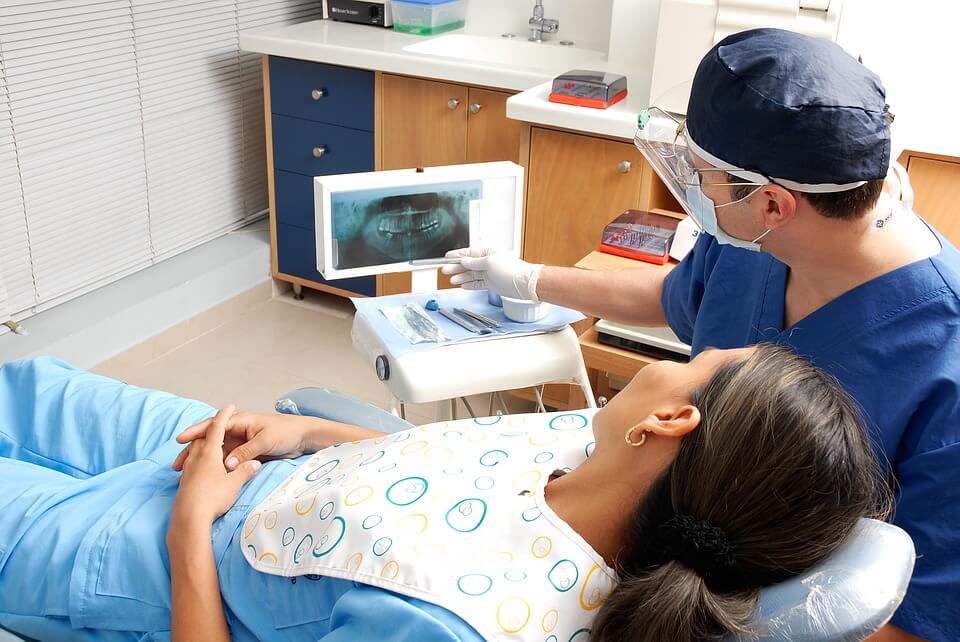 A dentist shows a patient an x-ray of their teeth, with visible fillings.