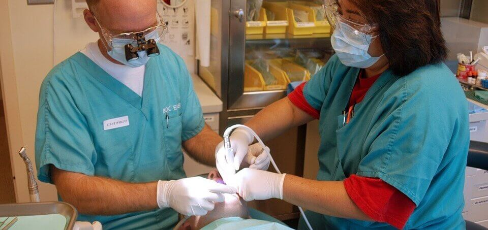Dentists examine a patient's teeth.