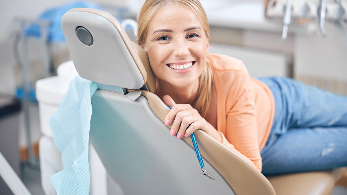 Woman sitting in a dentist chair smiling.