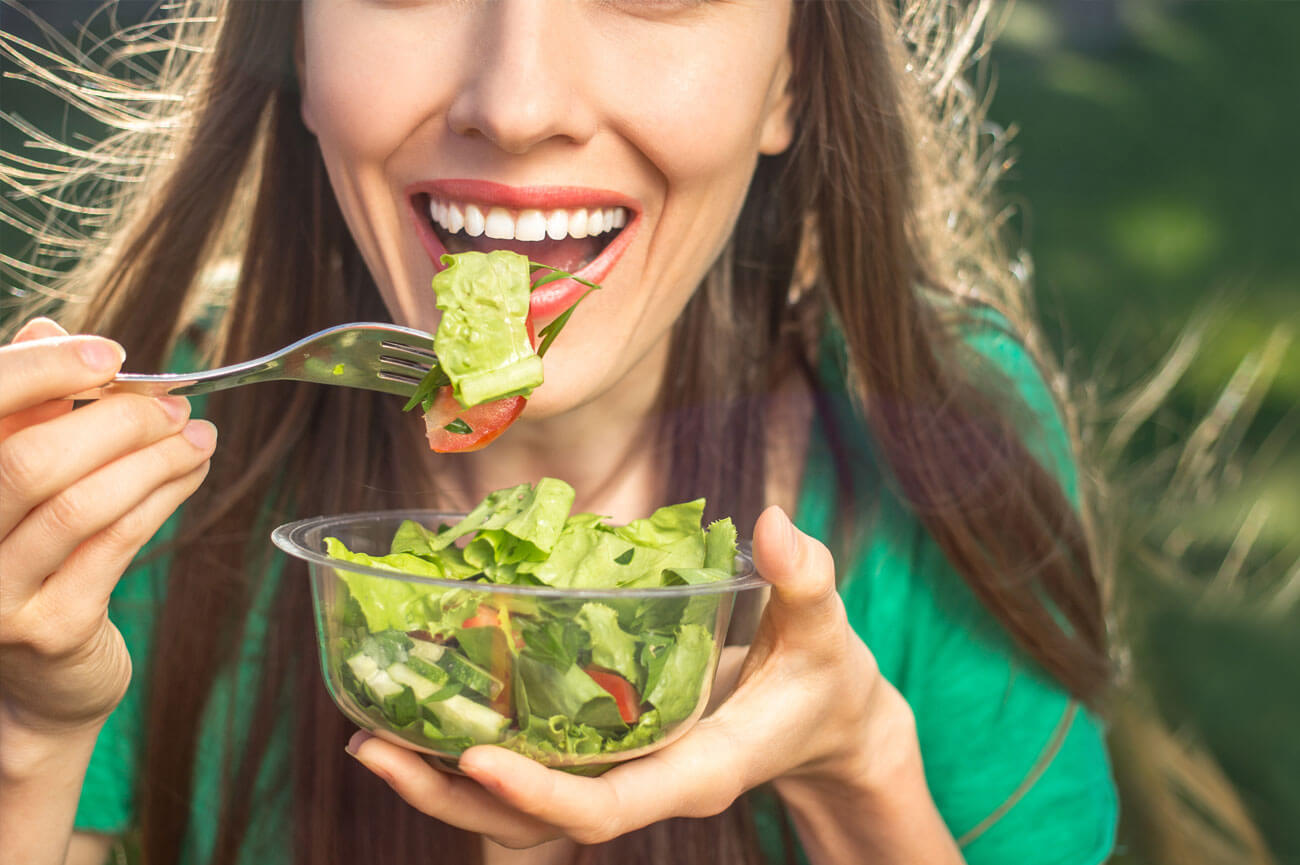 Smiling women eating a healthy bowl of salad